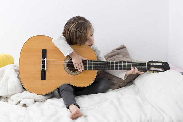 Little girl learning to play classical guitar - 写真・画像