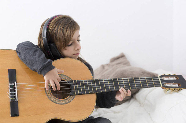 Menina aprendendo a tocar guitarra clássica
 - Foto, Imagem