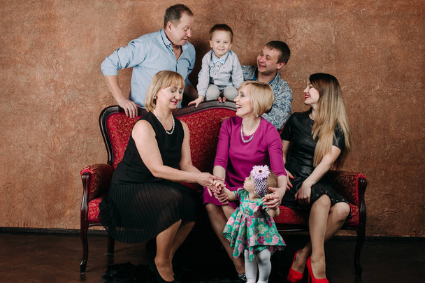 Сім'я трьох поколінь сидить на дивані разом. Класичний портрет
 - Фото, зображення