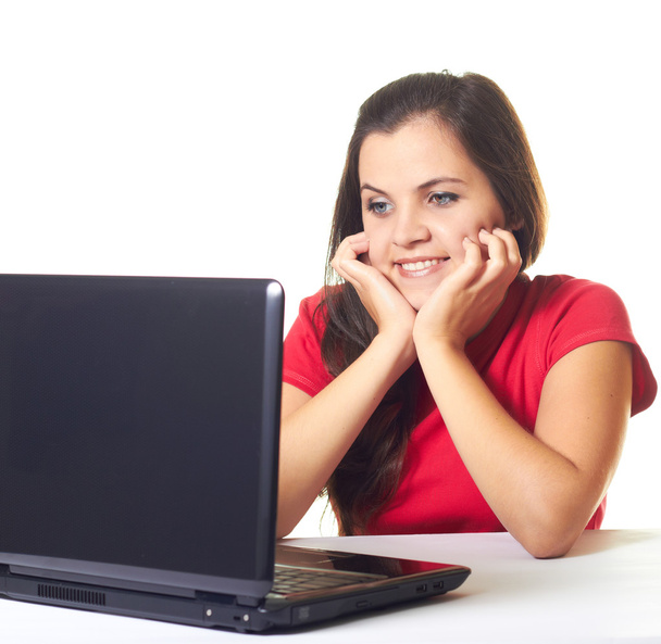aantrekkelijke jonge lachende meisje in rood shirt die op laptop werkt en - Foto, afbeelding