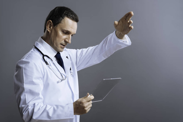 Smart doctor gesturing with medical glass - Foto, afbeelding