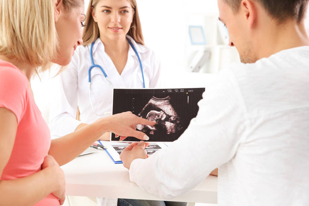 Gynecology consultation. Doctor showing ultrasound scan  of baby to couple - Foto, Bild