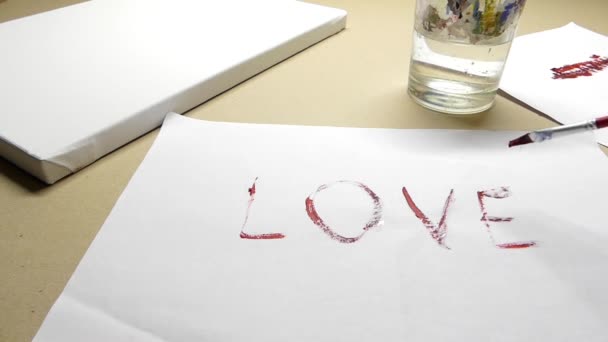 Ręczne malowanie 'miłość' z płaskiej końcówki pędzla na arkuszu papieru - Materiał filmowy, wideo