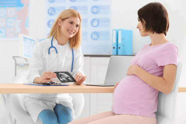 Doctor showing ultrasound photo to pregnant woman - Fotoğraf, Görsel