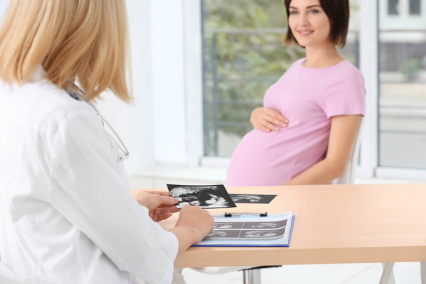 Doctor showing ultrasound photo to pregnant woman - Foto, Bild