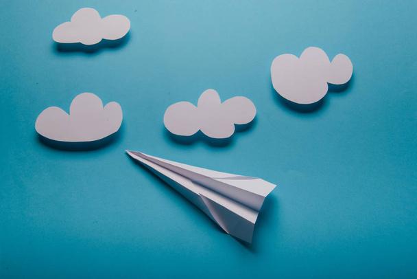 Avion en papier à la main féminine sur fond bleu avec nuages
 - Photo, image