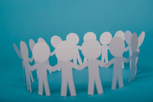 абстрактные бумажные люди, держащиеся за руки на синем фоне - Фото, изображение