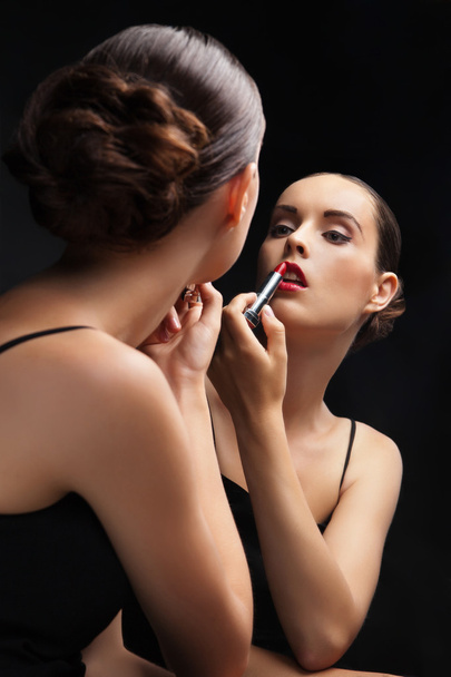 Beautiful young woman near mirror with lipstick - Photo, Image