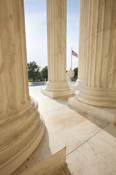 Bandera americana vista entre pilares del edificio de la Corte Suprema
 - Foto, imagen