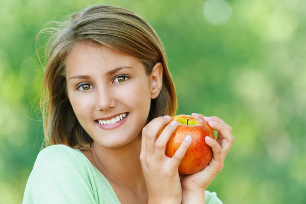 улыбающаяся красивая молодая женщина с яблоком
 - Фото, изображение