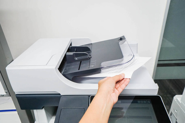 Frau bringt ausgedruckte Dokumente aus Druckermaschine mit - Foto, Bild