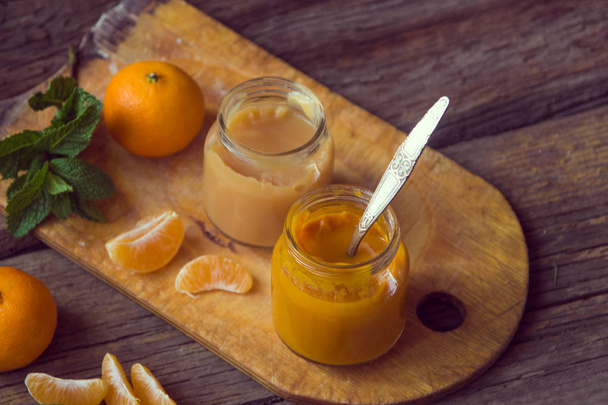 Vasi di vetro con alimenti naturali per bambini con mandarino sulla t di legno
 - Foto, immagini