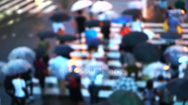 Blur city pedestrian crossing road junction with umbrellas in rainy day - Footage, Video