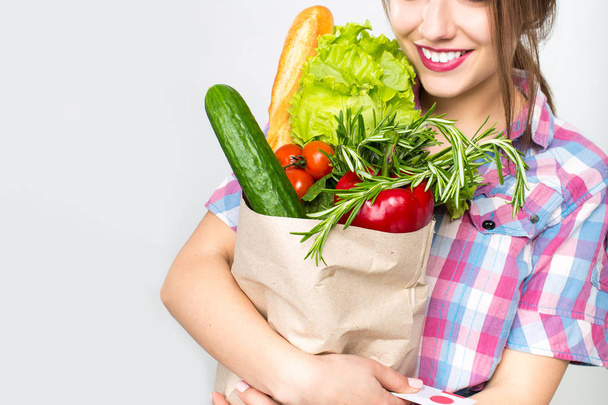 Beautiful smiling woman holding shopping paper bag with organic fresh food - Foto, afbeelding