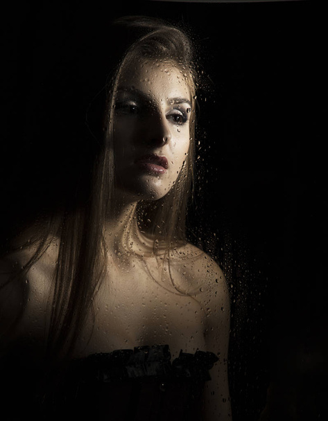 Portrait of a sensual young sexy woman wearing corset, touching her hair on black background - Fotografie, Obrázek