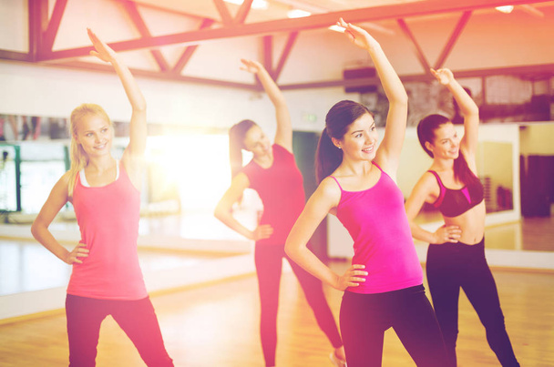 group of smiling people stretching in the gym - Foto, Bild