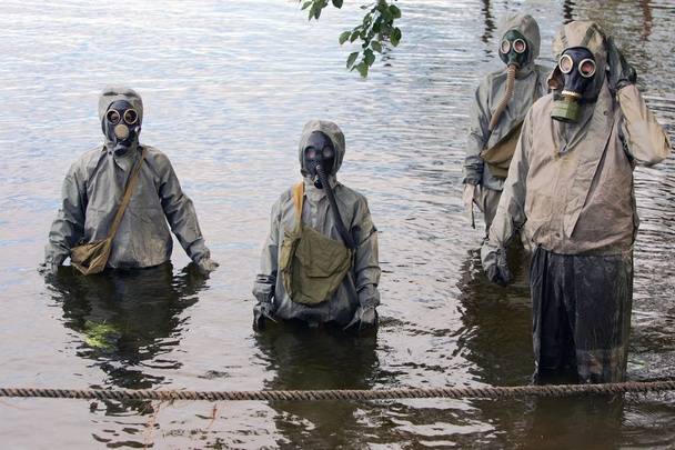 Les gens avec des masques à gaz se déplacent sur la rivière pour des enseignements défensifs
 - Photo, image