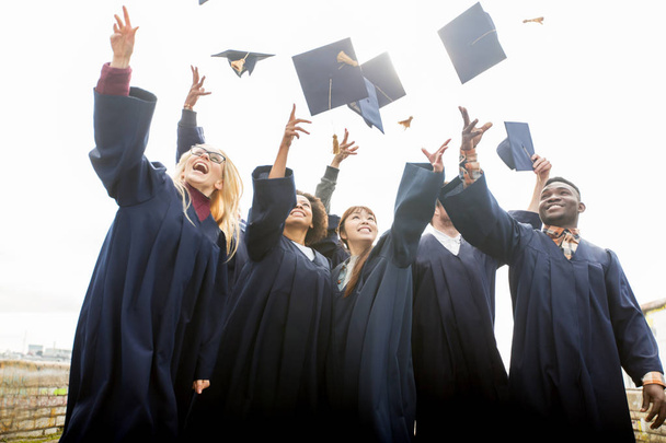 happy students throwing mortar boards up - Photo, Image