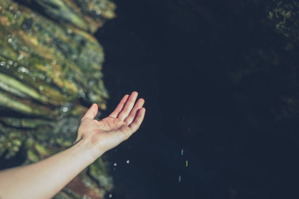 The hand of a young woman is catching some water drops in a cave - Φωτογραφία, εικόνα