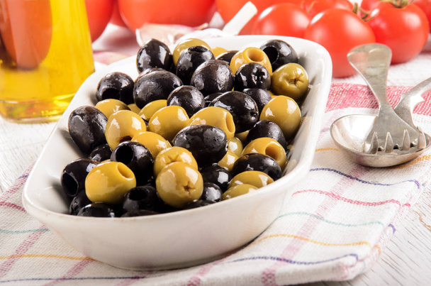 olives vertes et noires dans un bol, tomates et huile d'olive dans le
  - Photo, image
