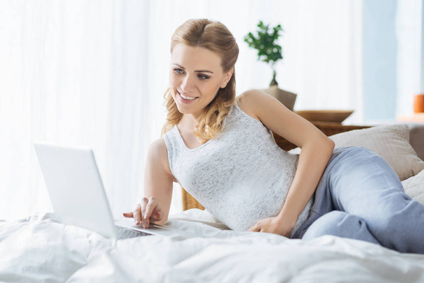 Relaxed pregnant woman using laptop in bedroom - Φωτογραφία, εικόνα