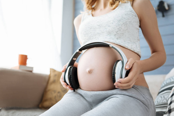 Close up of pregnant woman listening to music on headphones - Fotografie, Obrázek