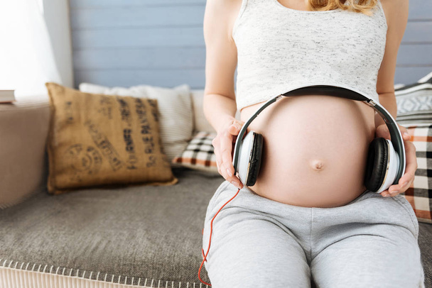 Close up of pregnant woman using headphones on her belly - Φωτογραφία, εικόνα