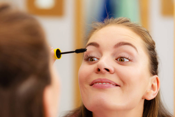 Woman applying black eye mascara to her eyelashes  - Fotografie, Obrázek