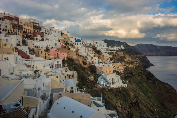 White city on a slope of a hill at sunset, Oia, Santorini, Greec - Photo, Image