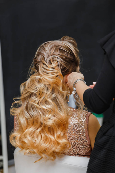 peluquero haciendo peinado de cola a mujer joven con cabello dorado en la barbería
 - Foto, Imagen