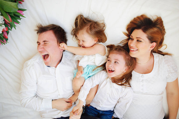 Big close-knit family from four people cheerfully spends time for beds - Foto, immagini