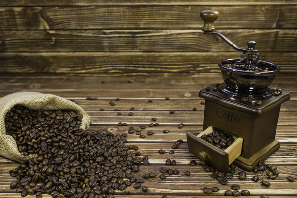 Sack coffee with grinder on a wooden background - Fotó, kép