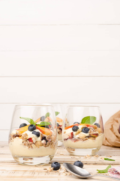 Granola com pêssegos, iogurte e mirtilos
 - Foto, Imagem
