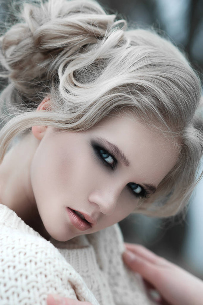 Close up van mooie jonge blonde vrouw met blauwe ogen in de witte trui. - Foto, afbeelding