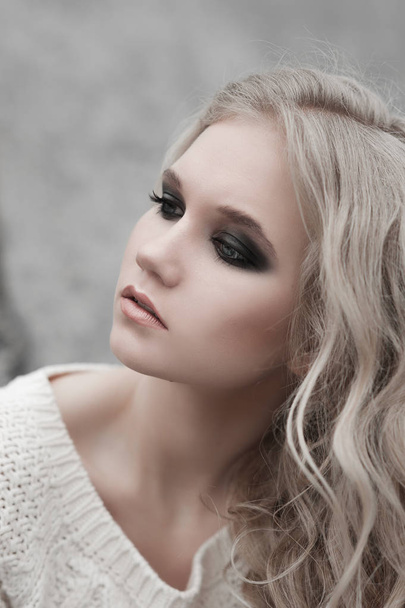 Close up van mooie jonge blonde vrouw met blauwe ogen in de witte trui. - Foto, afbeelding