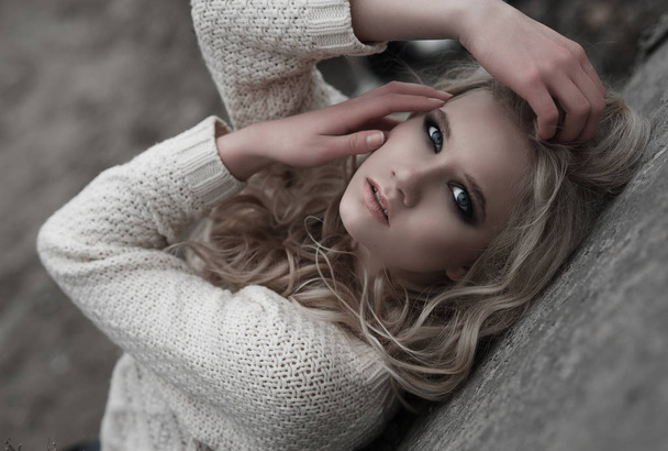 Zblízka krásná mladá blondýnka s modrýma očima v bílý svetr. - Fotografie, Obrázek