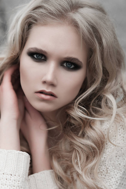 Nahaufnahme einer schönen jungen blonden Frau mit blauen Augen im weißen Pullover. - Foto, Bild