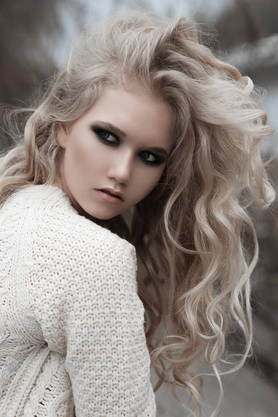 Nahaufnahme einer schönen jungen blonden Frau mit blauen Augen im weißen Pullover. - Foto, Bild