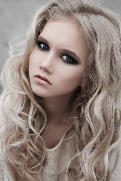 Gros plan de belle jeune femme blonde aux yeux bleus en pull blanc
. - Photo, image