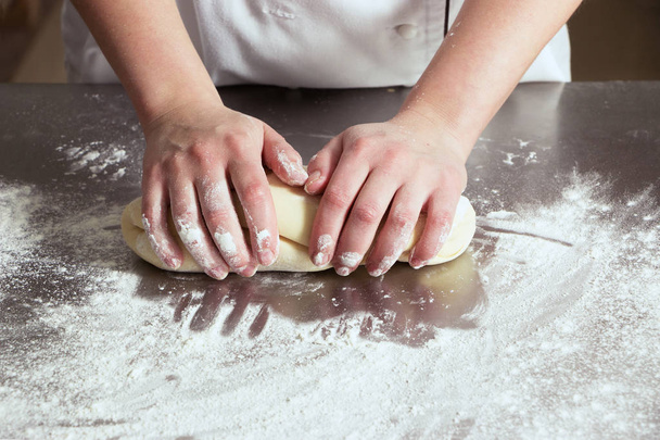 Γυναίκα Ζυμώστε τη ζύμη στο φούρνο, σε ένα τραπέζι από χάλυβα. Διαδικασία εργασίας - Φωτογραφία, εικόνα