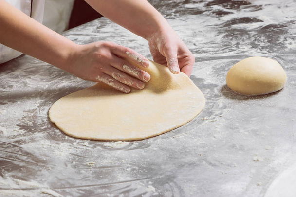 Γυναίκα που εργάζεται με τη ζύμη στο φούρνο, σε ένα τραπέζι από χάλυβα. Διαδικασία εργασίας - Φωτογραφία, εικόνα
