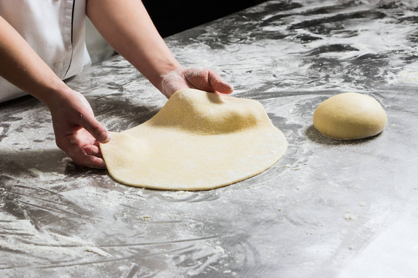Woman working with dough in bakery, on a table from steel. Working process - Photo, image