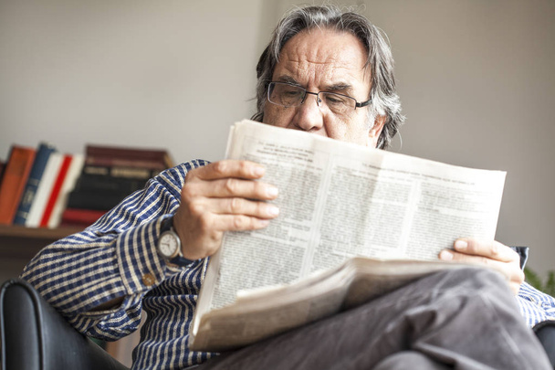 Старший чоловік читає газету
 - Фото, зображення