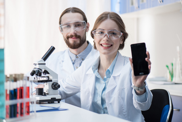 Female scientist showing smartphone - Foto, Imagen