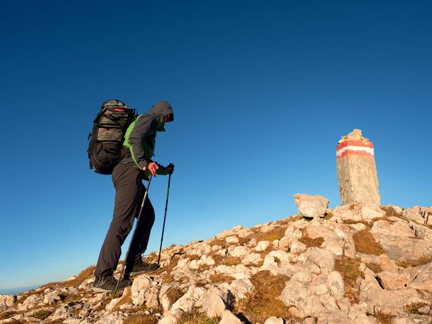 Turisti pylväät ja reppu kävellä vuoren huipulle. Viimeinen askel huippukokoukseen
 - Valokuva, kuva