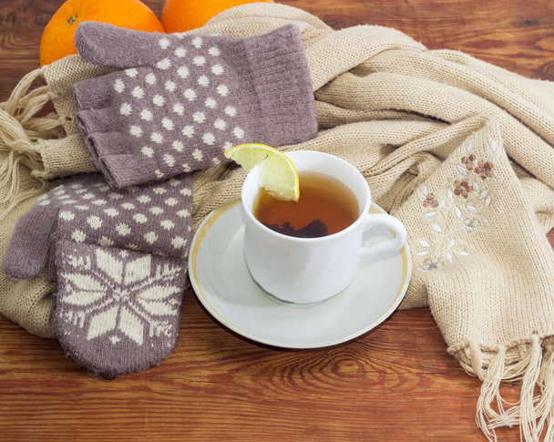 Tasse Tee auf dem Hintergrund von Wollhandschuhen und Schal - Foto, Bild