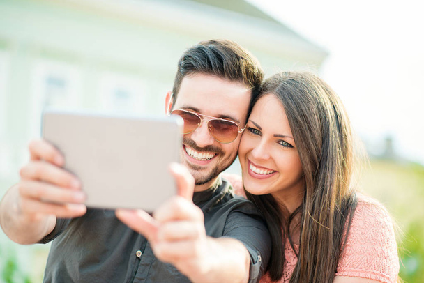 Selfie を取って愛情若いカップルのショットをトリミング - 写真・画像