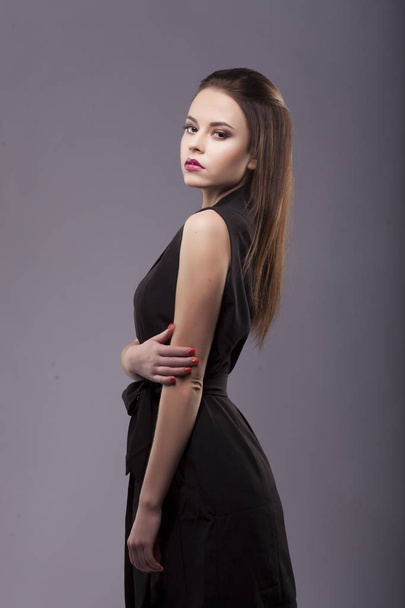 shoulder turned to camera, sexy beautiful brunette with long natural hair make up, in black sleeveless costume suit - Photo, Image