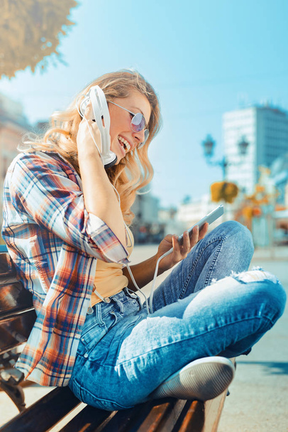 Νεαρή γυναίκα να ακούτε μουσική σε ένα έξυπνο τηλέφωνο - Φωτογραφία, εικόνα