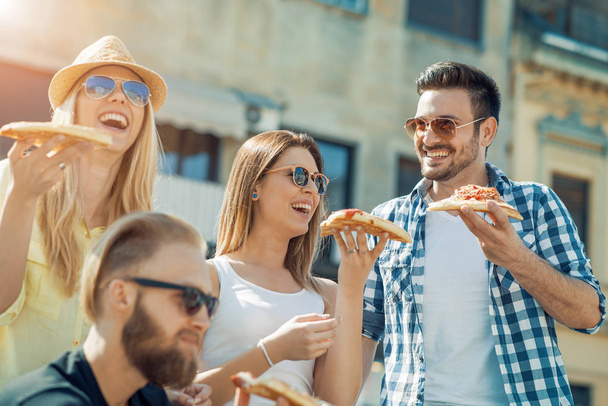 Grupo de amigos tomando sus rebanadas de pizza
 - Foto, Imagen